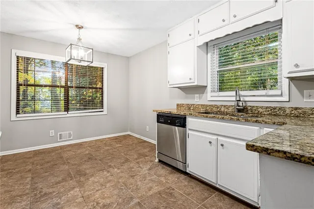 a kitchen with granite countertop a sink window and cabinets