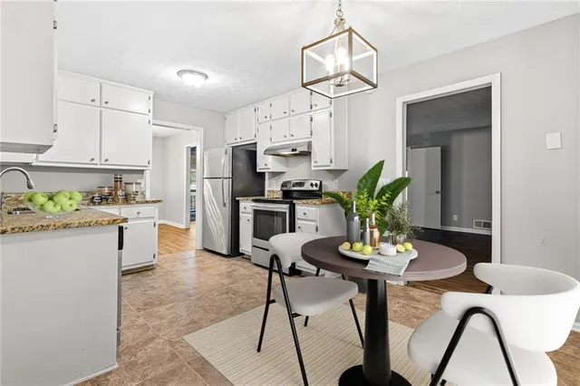 a kitchen with stainless steel appliances kitchen island granite countertop a table chairs stove and white cabinets