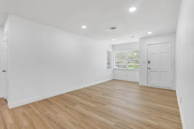 a view of an empty room with wooden floor and a window