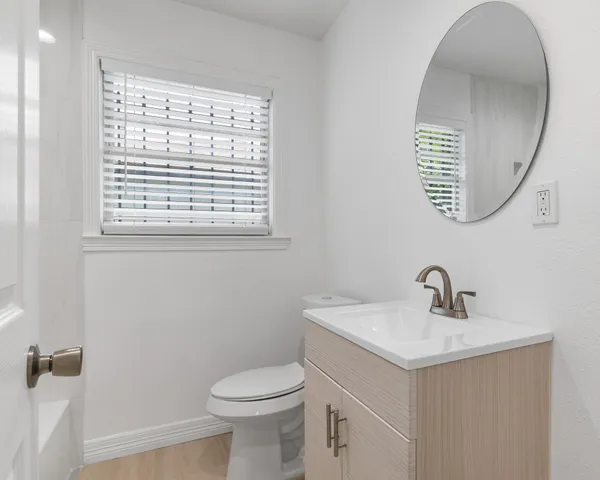 a bathroom with a sink a mirror a toilet and a window