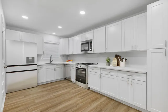 a kitchen with granite countertop white cabinets and stainless steel appliances