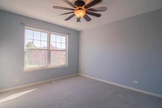 an empty room with window and chandelier fan