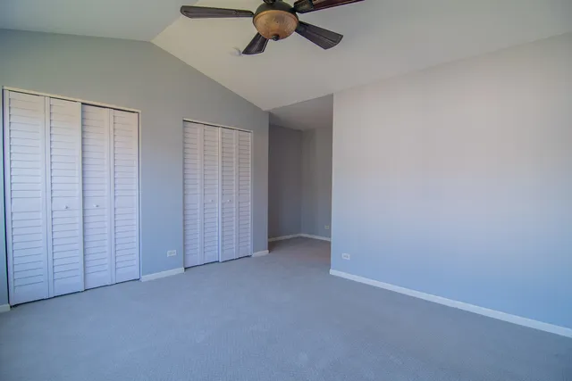 an empty room with a ceiling fan and carpet
