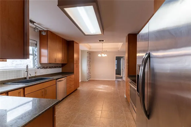 a kitchen with stainless steel appliances granite countertop a sink and a refrigerator