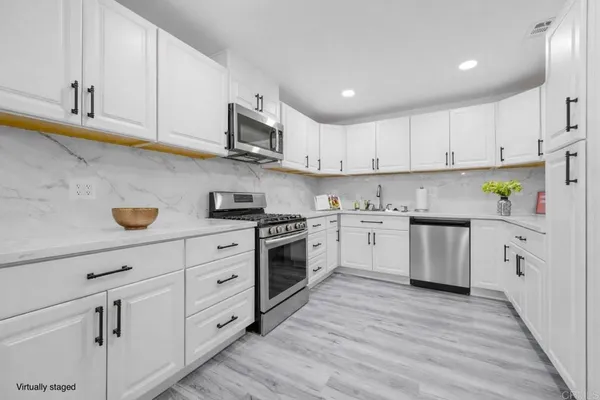 a kitchen with cabinets stainless steel appliances a sink and wooden floor