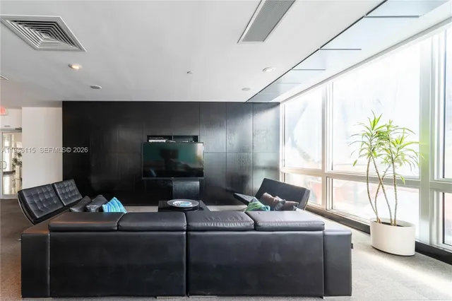 a living room with furniture floor to ceiling window and a flat screen tv