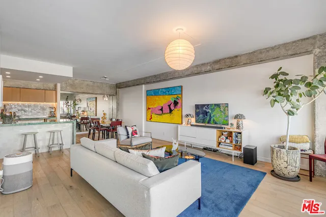 a living room with furniture kitchen view and a wooden floor