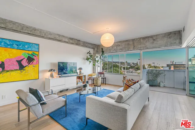 a living room with furniture kitchen view and a large window