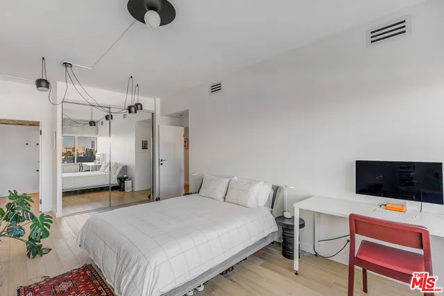 a bedroom with a bed a flat screen tv and a couch