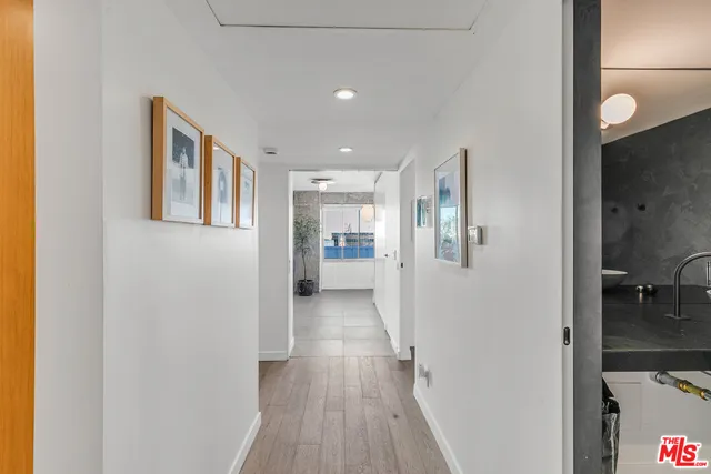 a view of a hallway with wooden floor and a bathroom