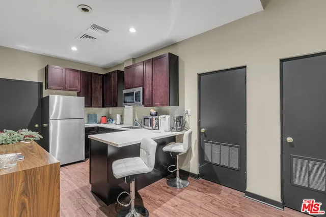 a kitchen that has a refrigerator a sink and chairs