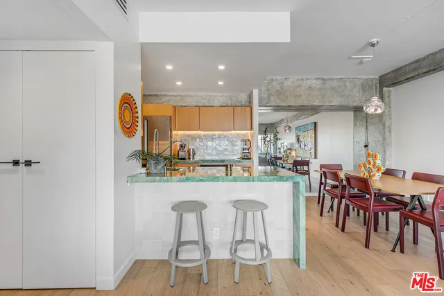 a kitchen with stainless steel appliances kitchen island granite countertop a dining table chairs and a refrigerator