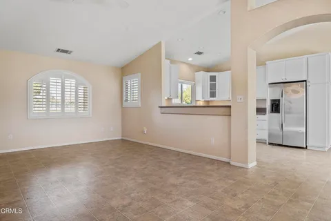 an empty room with windows and refrigerator