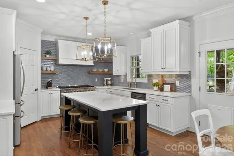 a kitchen with stainless steel appliances kitchen island a table chairs and a refrigerator