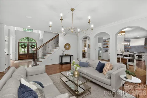 a living room with furniture kitchen view and a chandelier