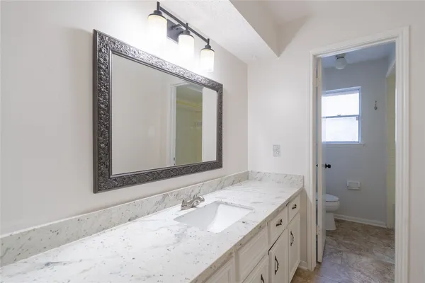 a bathroom with a granite countertop sink mirror and a toilet