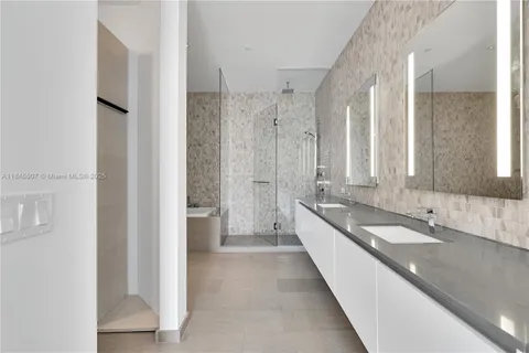 a large en suite bathroom with a double vanity sink a large mirror and a bathtub