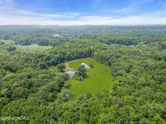 an aerial view of residential house with outdoor space and trees all around