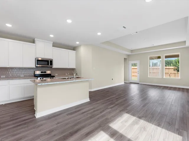 a kitchen with granite countertop wooden floors stainless steel appliances and window