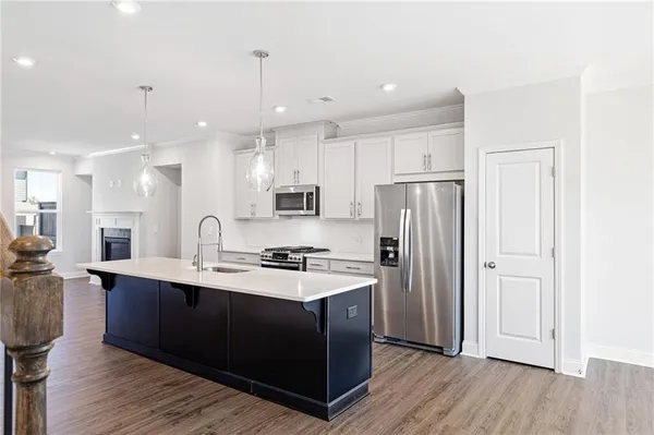 a kitchen with stainless steel appliances granite countertop a refrigerator a sink dishwasher a stove and white countertops with wooden floor