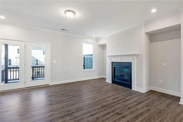 an empty room with wooden floor fireplace and windows