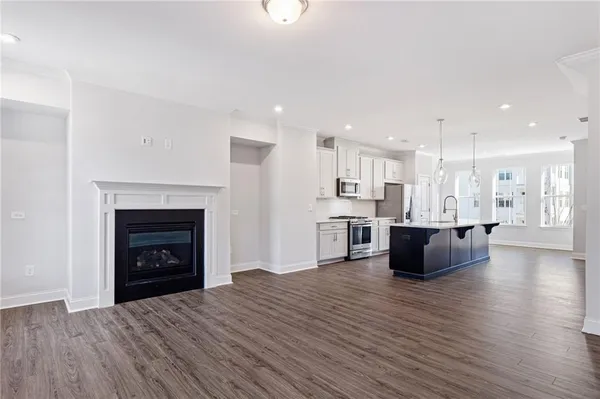 a large living room with stainless steel appliances wooden floor and a fireplace