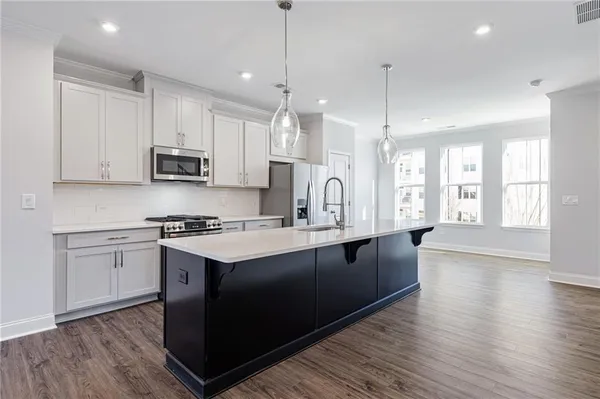 a kitchen with stainless steel appliances granite countertop a sink a stove and a wooden floors