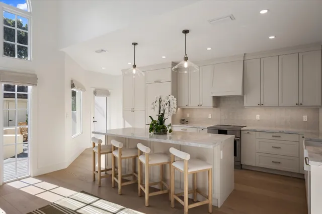a kitchen with stainless steel appliances kitchen island granite countertop a table chairs and a refrigerator