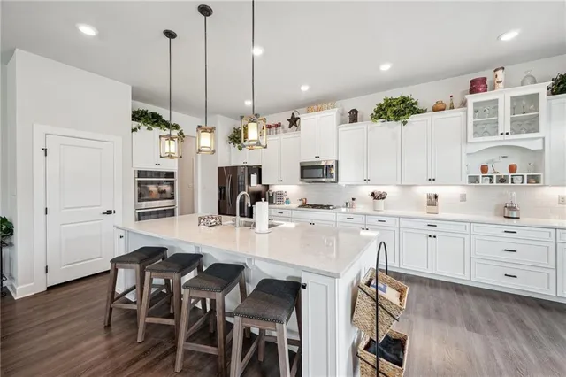 a kitchen with stainless steel appliances kitchen island granite countertop a table chairs and white cabinets