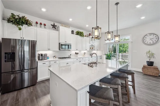 a kitchen with kitchen island a refrigerator a stove a dining table and chairs with wooden floor