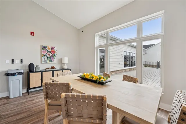 a kitchen with stainless steel appliances a refrigerator a stove a dining table and chairs with wooden floor