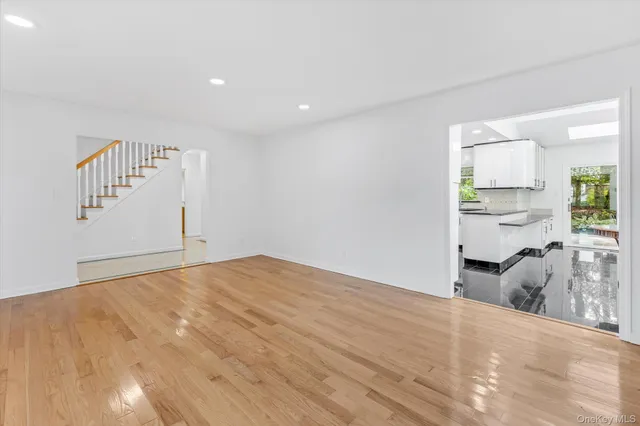 a kitchen with stainless steel appliances a refrigerator a sink a stove a dining table and chairs with wooden floor