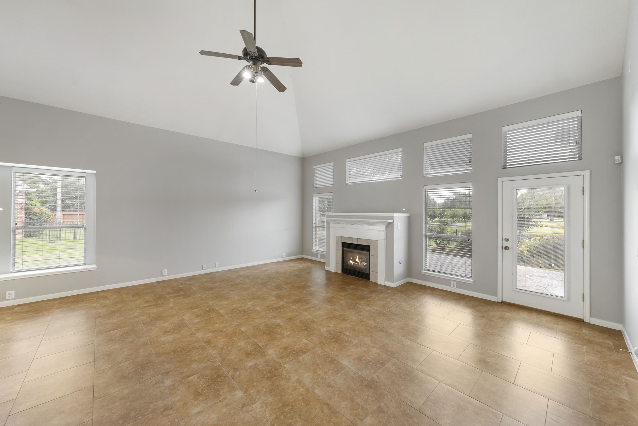 2907 Stemwood Drive Spring, TX 77388 - Photo 11 of 33 Expansive living room with soaring ceilings, abundant natural light, and a cozy fireplace overlooking peaceful waterfront views. Large windows and direct patio access create a bright, airy space ideal for relaxing or entertaining.