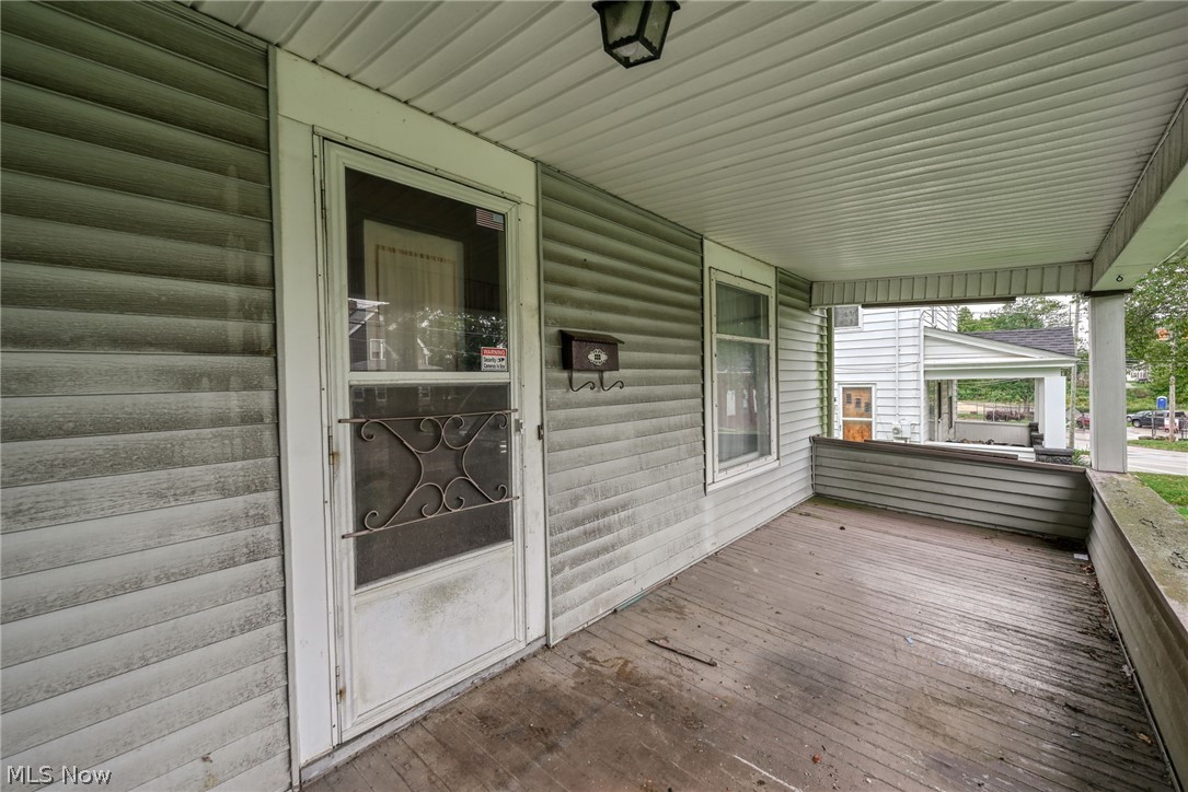 267 West Riddle Avenue Ravenna, OH 44266 - Photo 28 of 47 Covered front porch with composite decking, ornamental metal entry door with glass panels, horizontal vinyl siding in sage green, and aluminum-framed windows with white trim