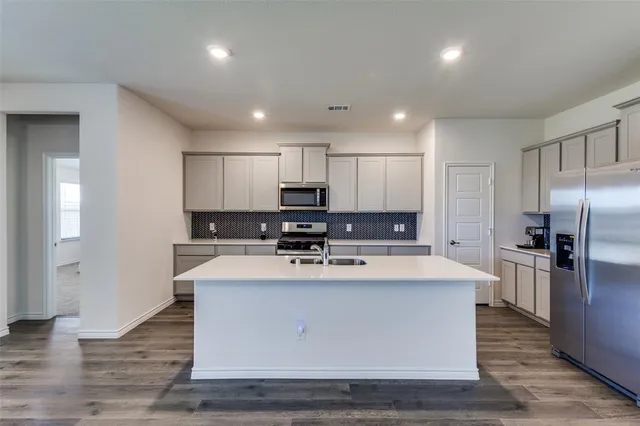 a large kitchen with stainless steel appliances lots of counter space and wooden floor