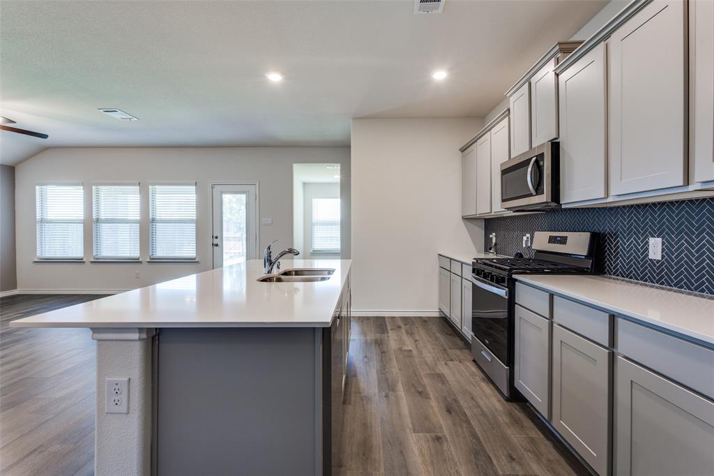6213 Abby Drive Aubrey, TX 76227 - Photo 11 of 32 a kitchen with stainless steel appliances granite countertop a sink a stove and a wooden floors