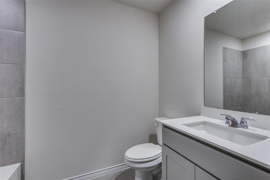 6213 Abby Drive Aubrey, TX 76227 - Photo 17 of 32 a bathroom with a granite countertop toilet and a sink