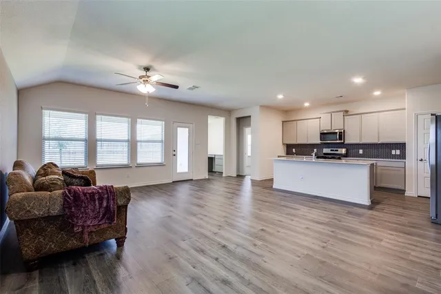 a large living room with stainless steel appliances granite countertop a couch a stove a sink and a large window