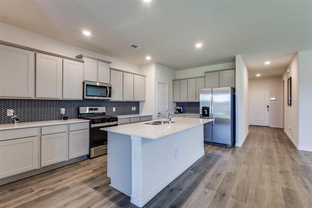 6213 Abby Drive Aubrey, TX 76227 - Photo 9 of 32 a large kitchen with stainless steel appliances lots of counter space and wooden floor