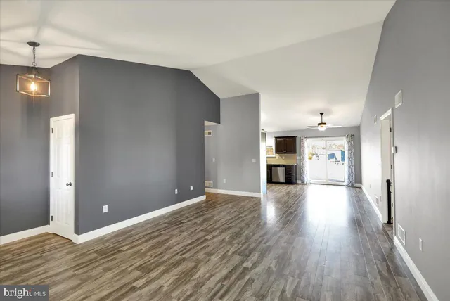 a view of an empty room with a kitchen and wooden floor