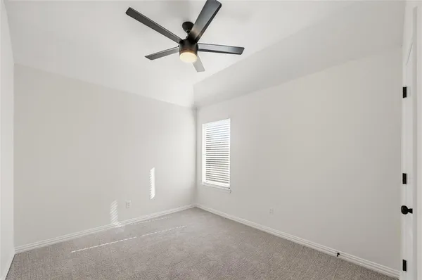 an empty room with a window and a fan