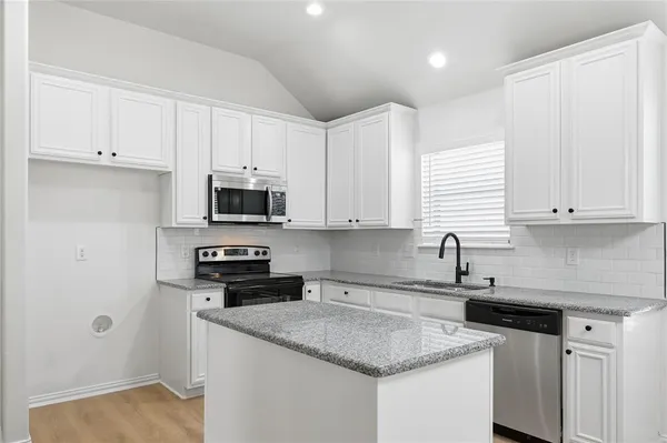 a kitchen with stainless steel appliances granite countertop a sink stove and microwave