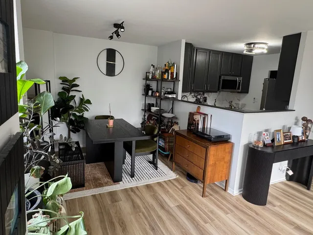 a living room with granite countertop couches a flat screen tv and kitchen view with wooden floor