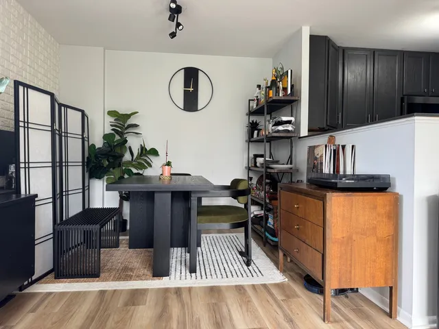 a kitchen with a refrigerator a stove and a dining table with wooden floor