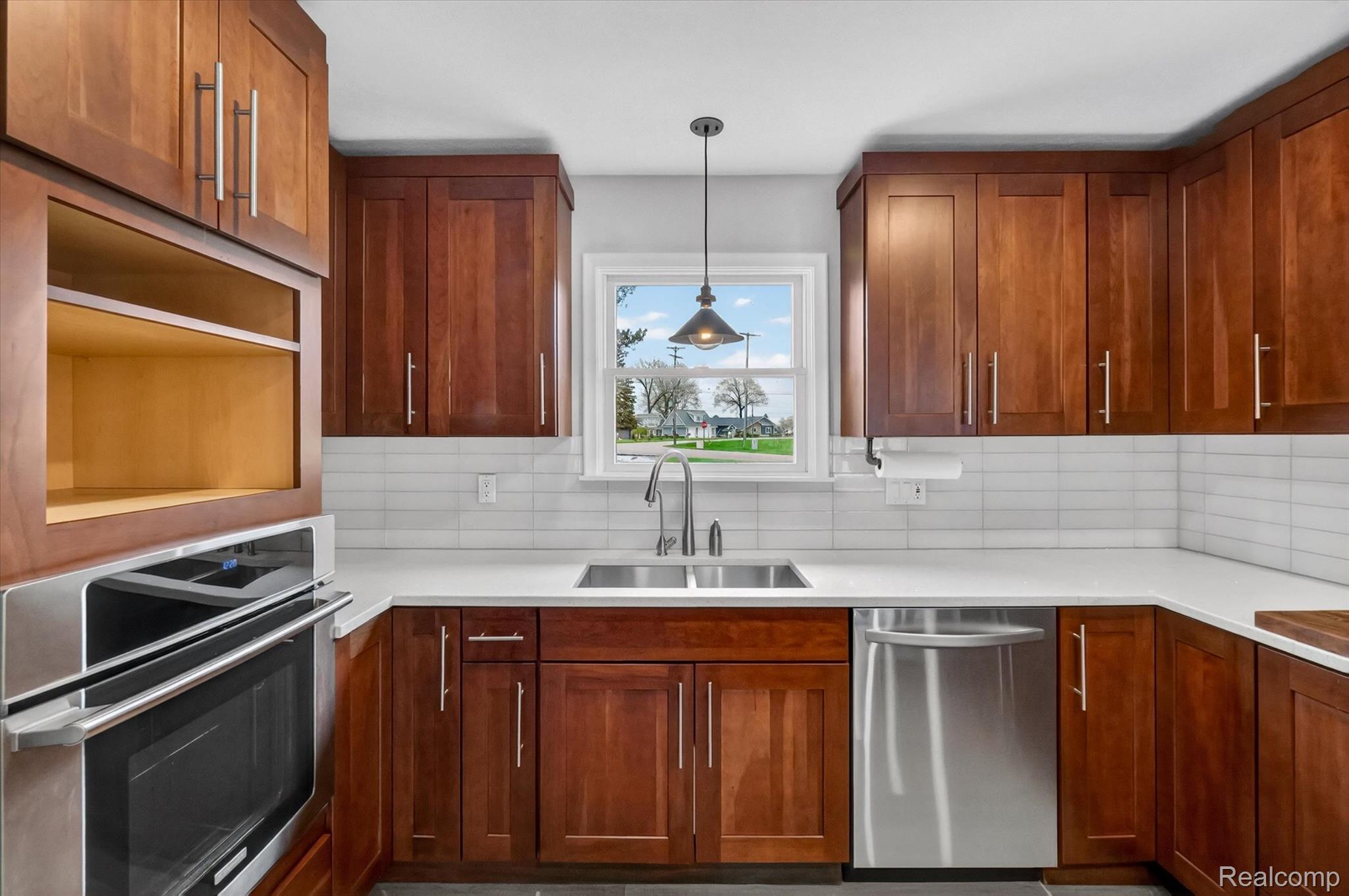 2264 Crane Road Fenton, MI 48430 - Photo 18 of 55 Kitchen featuring stainless steel appliances, wood finish cabinetry, hanging light fixtures, decorative backsplash, and light stone counters