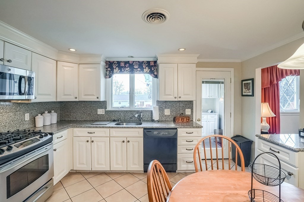 10 Sullivan Drive Randolph, MA 02368 - Photo 5 of 40 a kitchen with stainless steel appliances granite countertop a stove a sink dishwasher a dining table and chair with wooden floor
