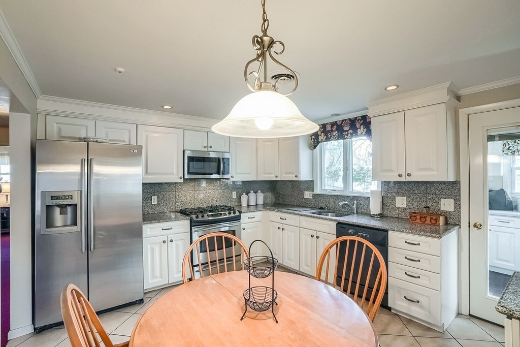 10 Sullivan Drive Randolph, MA 02368 - Photo 6 of 40 a kitchen with stainless steel appliances granite countertop a sink a stove a refrigerator cabinets and a dining table