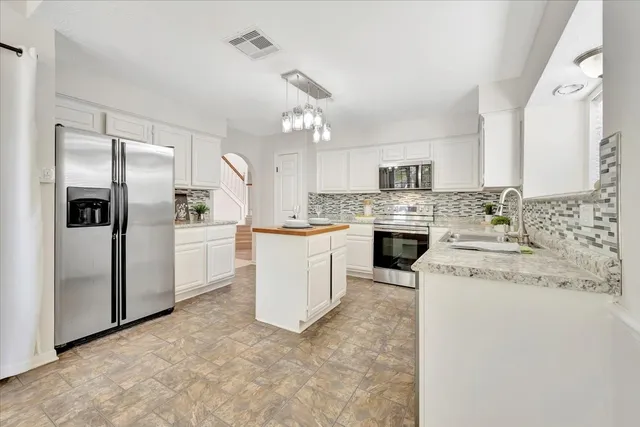 a kitchen with white cabinets and stainless steel appliances