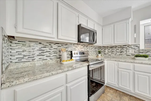 a kitchen with granite countertop white cabinets and stainless steel appliances