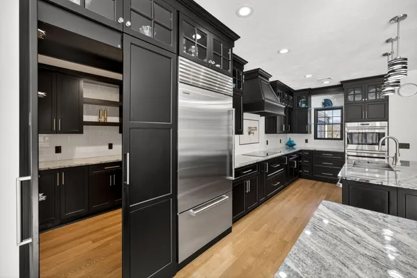 a large kitchen with stainless steel appliances granite countertop a refrigerator and a sink
